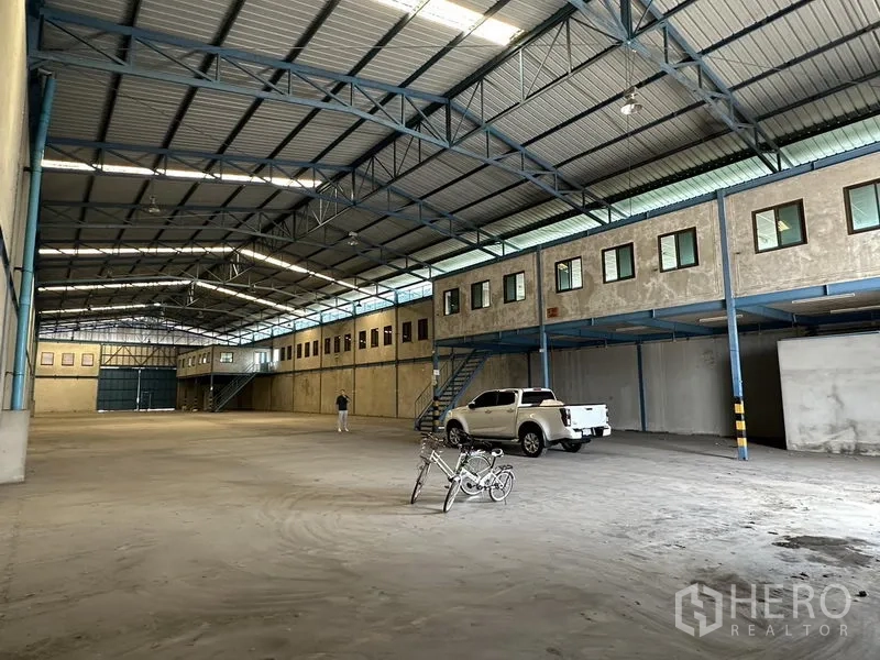 Warehouse for rent in Bang Phli, Samut Prakan - Open production and storage hall with mezzanine office rooms, pickup access, and bright roof lighting.
