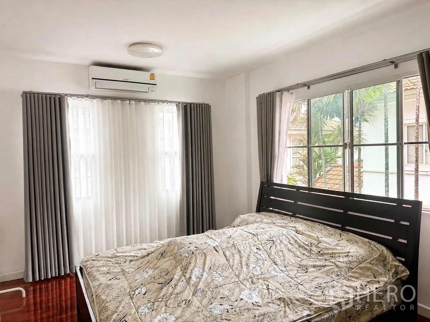 Detached House for rent in Prawet, Bangkok - Bedroom with bed, air conditioner above the windows, double curtains, and garden view.