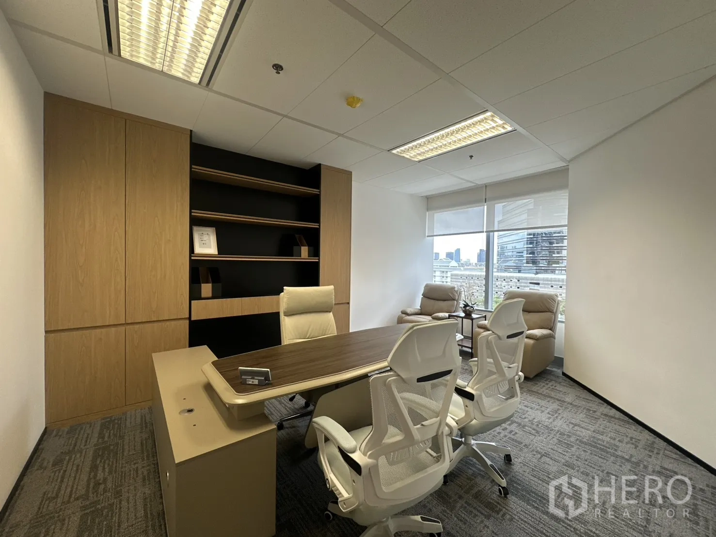 Office Space for rent in Pathum Wan, Bangkok - Executive office with wood desk, shelving, and two recliners by the window.