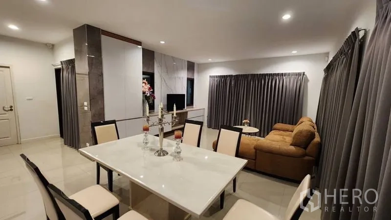 Detached House for rent in Prawet, Bangkok - Dining room with marble-top table and chairs overlooking the lounge with sofa.