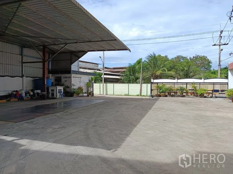 Factory for sale in Ban Phaeo, Samut Sakhon - Covered loading area with truck weighbridge and open concrete yard facing the gated entrance.