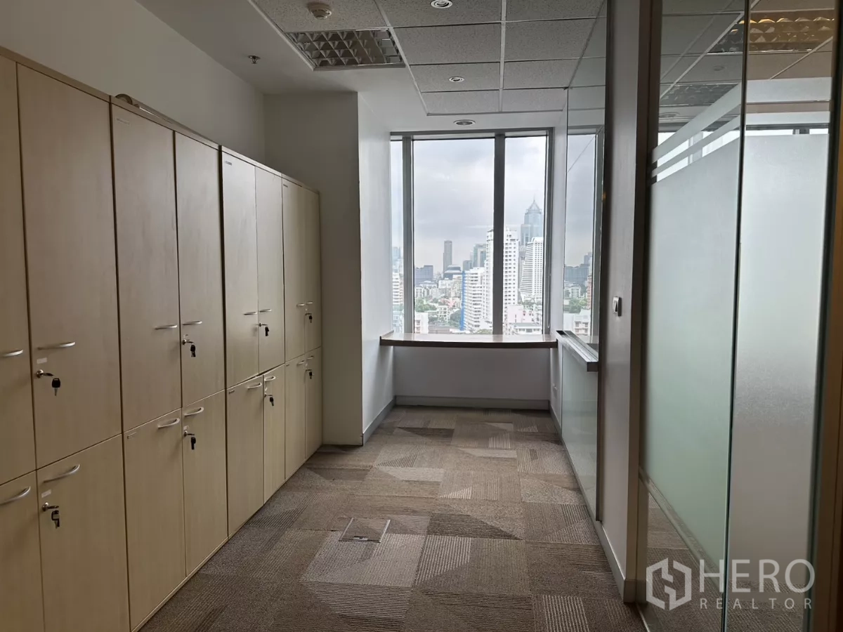 Office Space for rent in Watthana, Bangkok - Hallway lined with tall storage lockers facing a window with Bangkok skyline views.