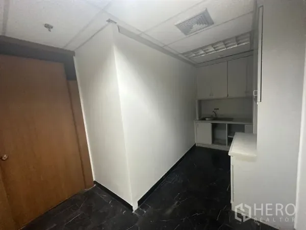 Office Space for rent in Pathum Wan, Bangkok - Compact pantry area with built-in cabinets, sink and dark tile floor inside the office.