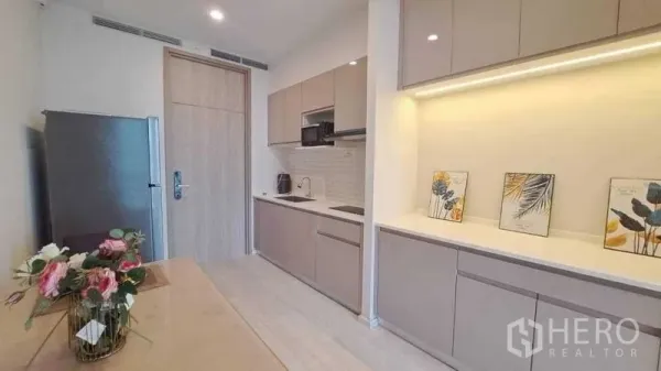 Condominium for rent or sale in Pathum Wan, Bangkok - Modern galley kitchen with built-in cabinets, under-cabinet lighting, and stainless fridge in a Bangkok condo.