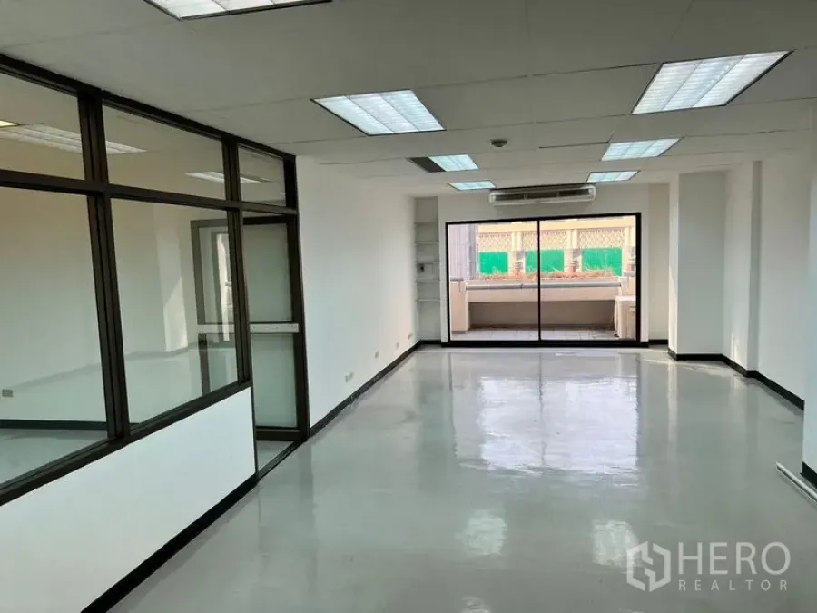 สำนักงาน ให้เช่าในPathum Wan, Bangkok - สำนักงานแบบโอเพนสเปซสว่าง พื้นเงางาม ไฟฟลูออเรสเซนต์ แอร์ผนัง และประตูกระจกบานเลื่อนออกสู่ระเบียง