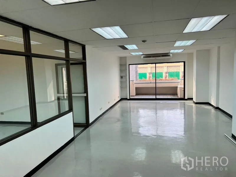 สำนักงาน ให้เช่าในPathum Wan, Bangkok - สำนักงานแบบโอเพนสเปซสว่าง พื้นเงางาม ไฟฟลูออเรสเซนต์ แอร์ผนัง และประตูกระจกบานเลื่อนออกสู่ระเบียง