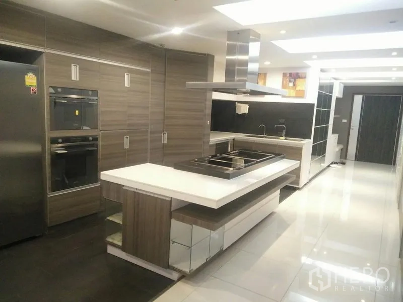 Condominium for rent or sale in Watthana, Bangkok - Gourmet kitchen featuring an island cooktop, built-in ovens, full-size fridge and ample cabinets.