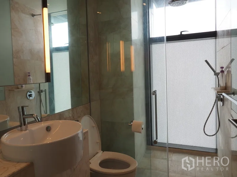 Condominium for rent in Sathon, Bangkok - Contemporary bathroom with rain shower, glass partition and marble-style finishes.