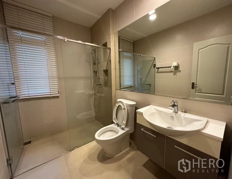 Detached House for rent or sale in Khan Na Yao, Bangkok - Guest bathroom with walk-in shower, vanity and toilet under soft lighting.