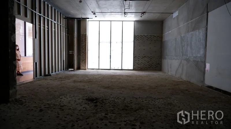 Retail Space for rent in Watthana, Bangkok - Deep retail unit with tall front windows, high ceilings and unfinished floors.