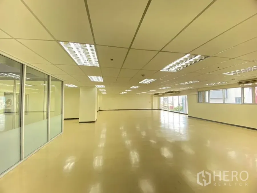 Office Space for rent in Watthana, Bangkok - Bright workspace with a long window wall, support columns, and fluorescent lighting.