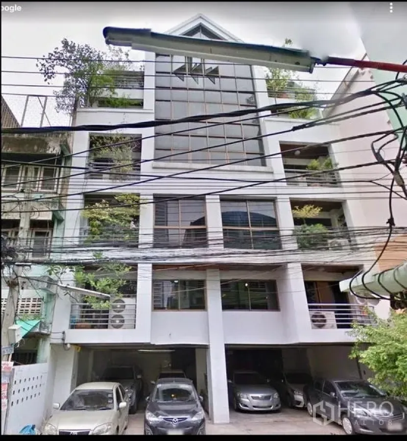 Office Space for sale in Ratchathewi, Bangkok - Mid-rise office building facade with glass front, leafy balconies and covered ground-floor parking.