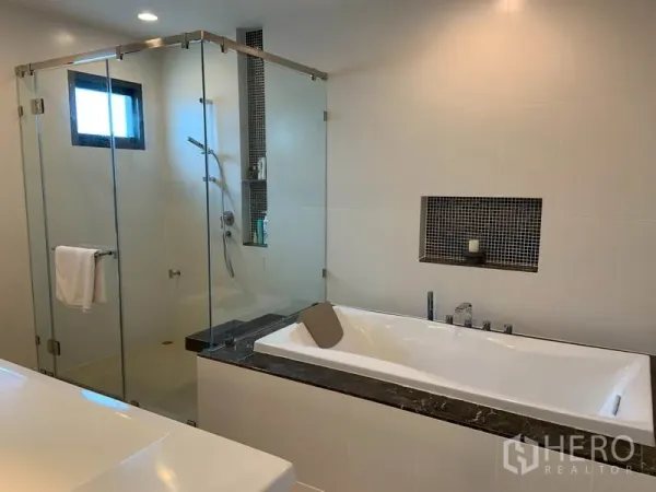Detached House for rent or sale in Bang Kapi, Bangkok - Modern bathroom with glass-enclosed shower and separate soaking bathtub.