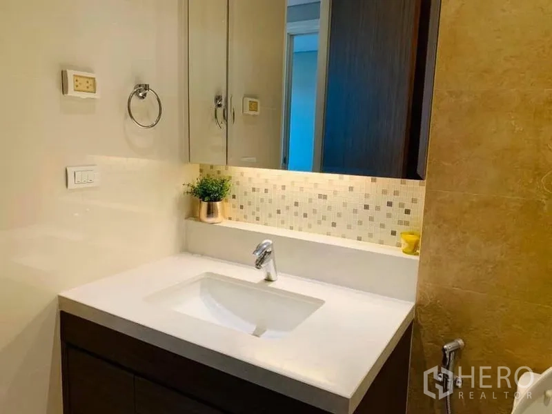 Condominium for rent in Khlong Toei, Bangkok - Vanity area with under-counter storage, mirror cabinet and mosaic backsplash lighting.
