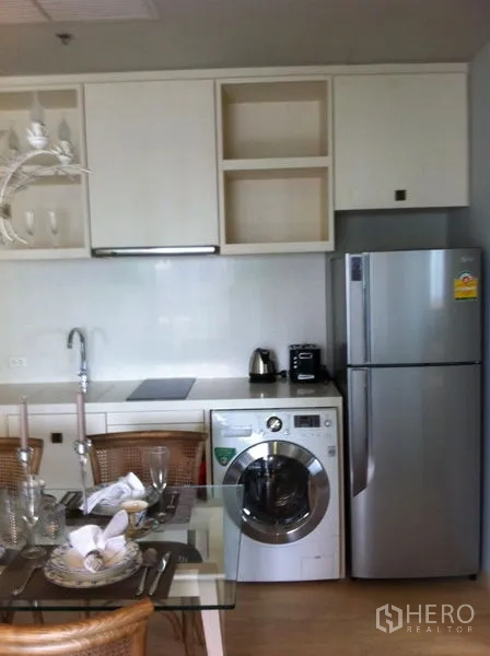 Condominium for rent in Bangkok - Appliance wall with stainless refrigerator and front-load washing machine.