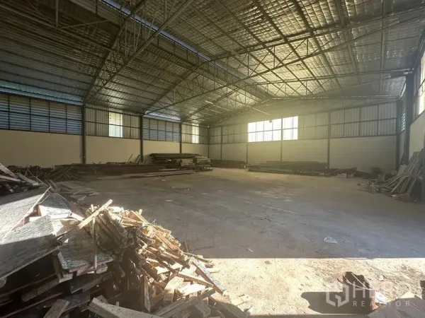 Warehouse for rent in Saphan Sung, Bangkok - Spacious warehouse interior with high steel truss roof, insulated panels, concrete floor and stacked timber.