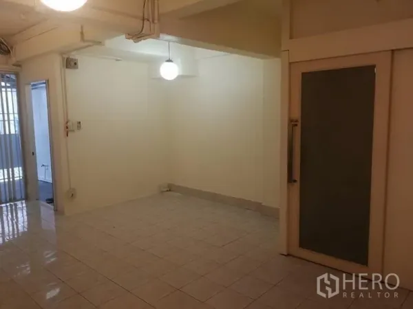 Townhouse for rent in Khlong Toei, Bangkok - Empty tiled living area with sliding glass door and pendant light in a Sukhumvit townhouse