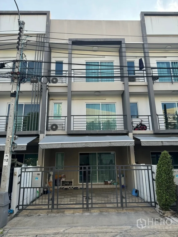 Townhouse for rent in Suan Luang, Bangkok - Three-storey modern townhouse facade with balconies and gated carport.
