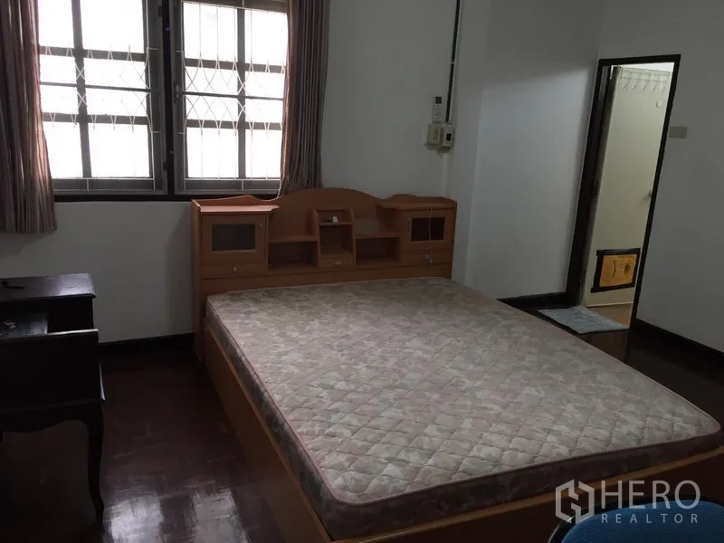 Townhouse for rent in Phra Khanong, Bangkok - Master bedroom with large bed, windows with bars and ensuite access.