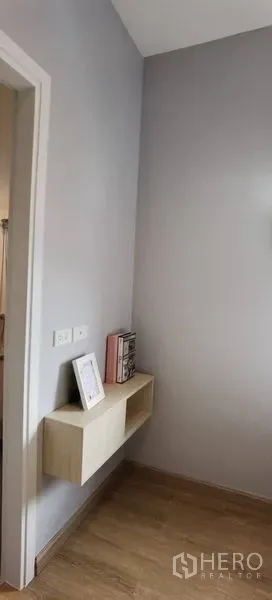 Townhouse for rent in Prawet, Bangkok - Small hallway with floating shelf on a light gray wall and wood flooring.
