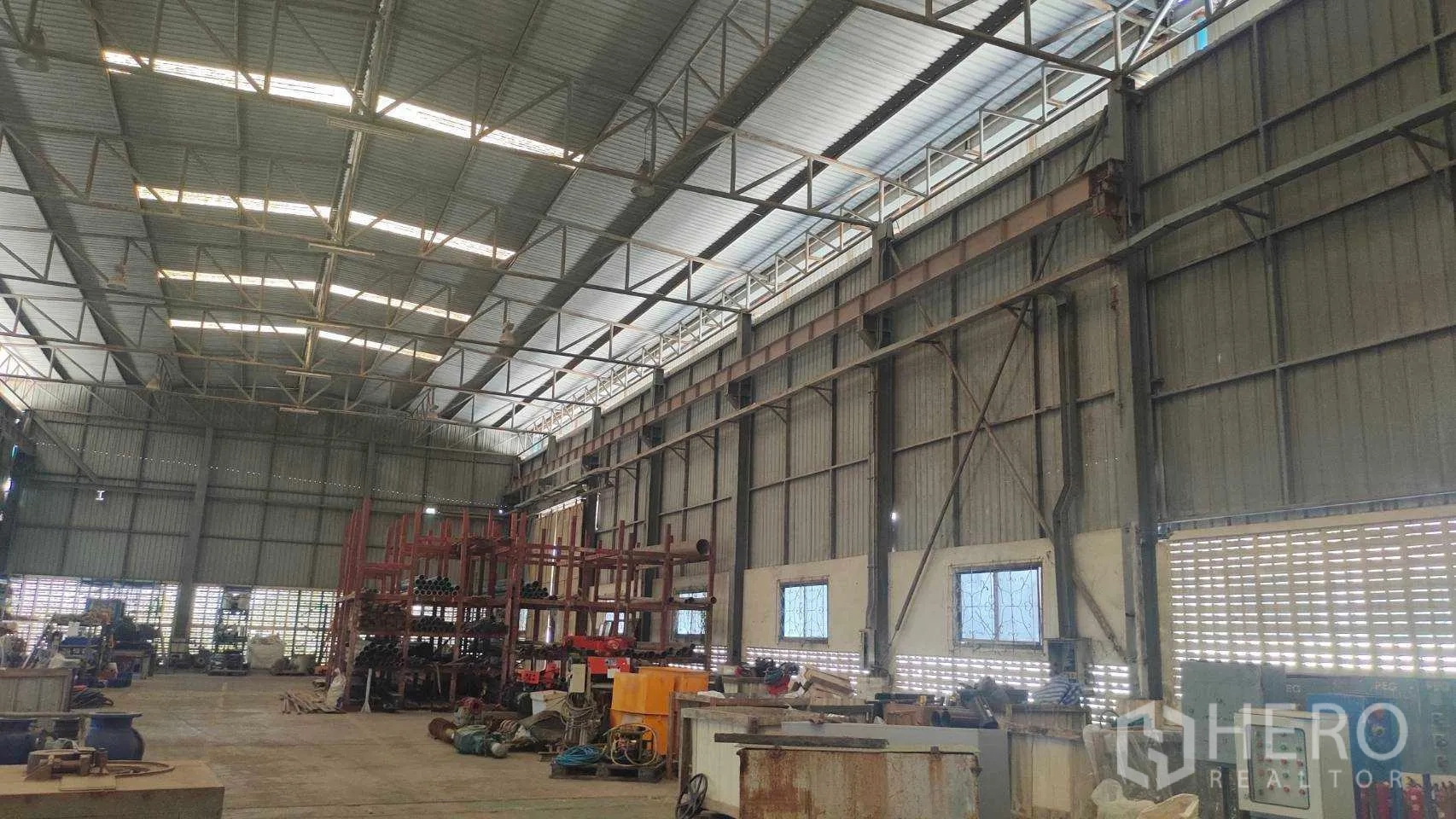 Factory for sale in Nikhom Phatthana, Rayong - Wide production area with high ceilings, storage racks and industrial equipment.
