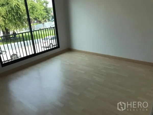 联排别墅 出租 - 二楼卧室，浅色复合木地板，大窗户可见街景与树木。
