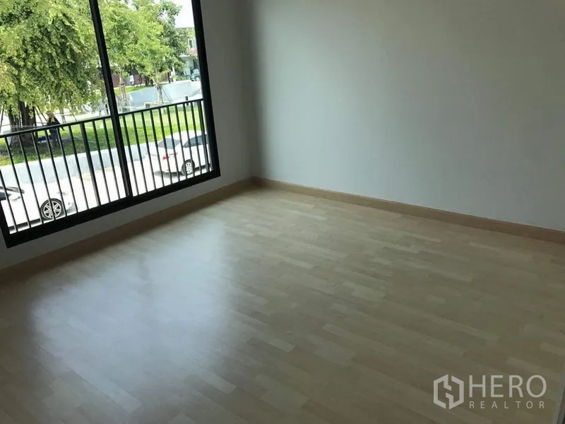 联排别墅 出租 - 二楼卧室，浅色复合木地板，大窗户可见街景与树木。