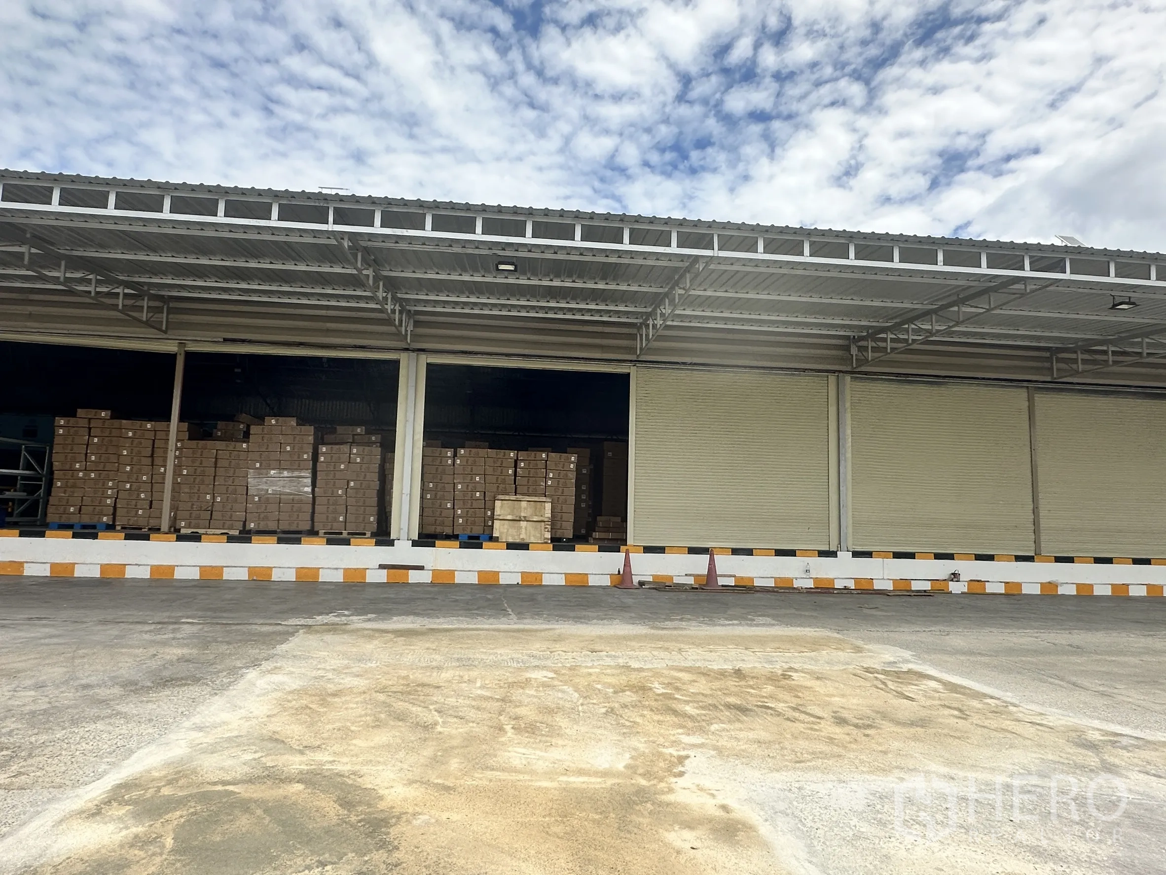 Factory for rent in Lat Krabang, Bangkok - Open loading bay showing stacks of cardboard boxes under a steel roof.