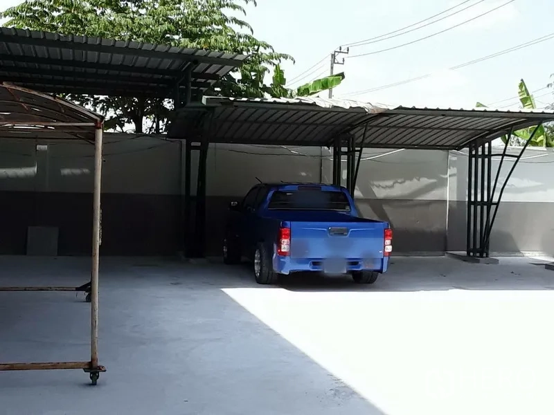 Factory for rent in Saphan Sung, Bangkok - Covered parking bays with metal canopies and a pickup truck on a concrete yard.