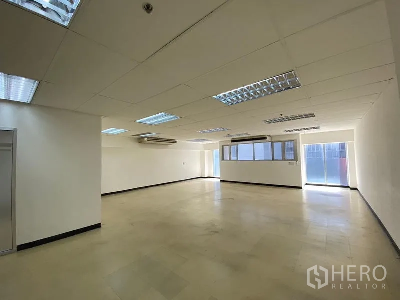 Office Space for rent in Watthana, Bangkok - Open-plan 130 sqm office with drop ceiling, fluorescent lighting, windows and split-type air conditioners.