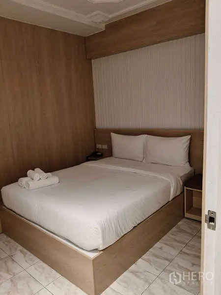 Retail Space for rent in Khlong Toei, Bangkok - Cozy room with double bed, bedside shelf and neutral wood decor.