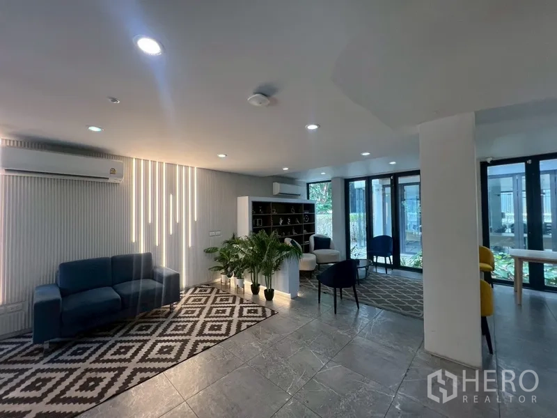 Home Office for rent or sale in Phra Khanong, Bangkok - Furnished lounge area with sofas, shelving and large windows.