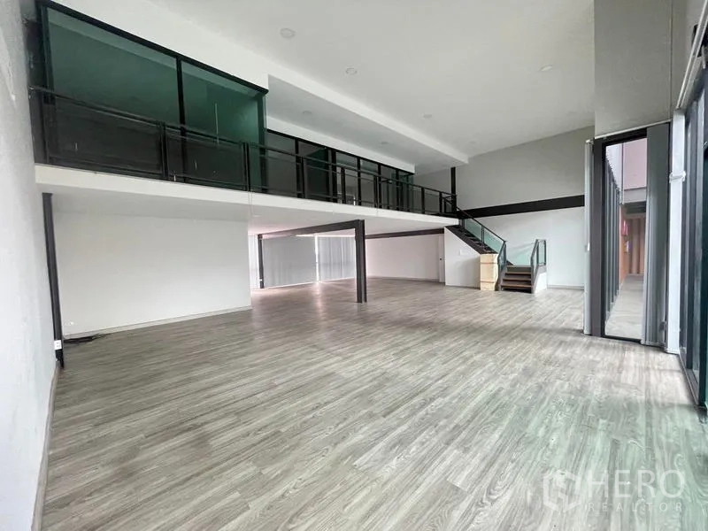 Office Space for rent in Bang Na, Bangkok - Spacious double-height office with mezzanine, glass railing, staircase and wood floors in Bang Na.