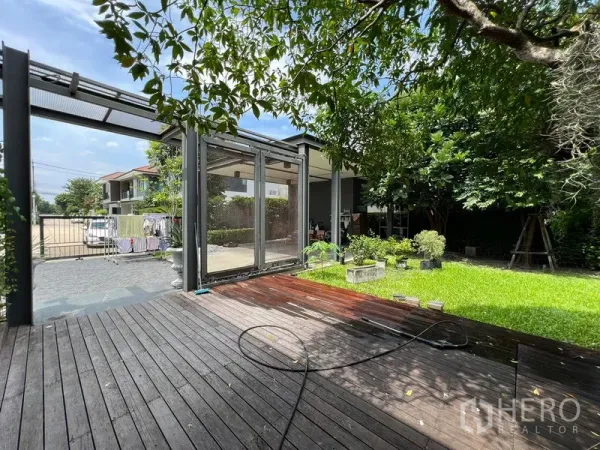 Detached House for sale in Bang Kapi, Bangkok - Shaded wooden terrace overlooking a private lawn and mature trees.