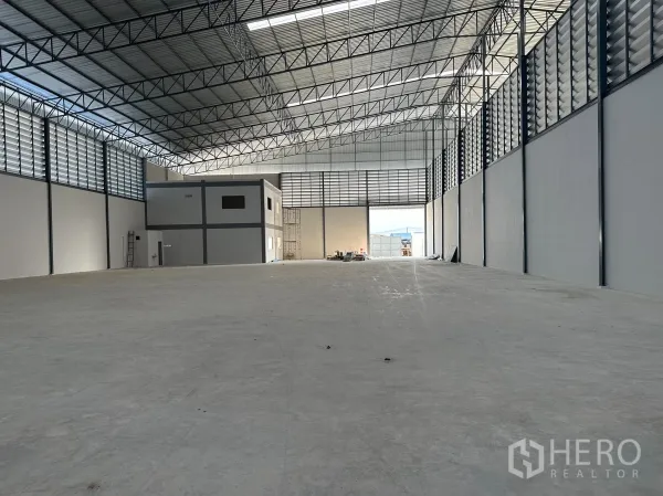 Factory for rent in Nong Khaem, Bangkok - Warehouse view toward large entry and two‑storey office block, bright natural light and clear span roof.