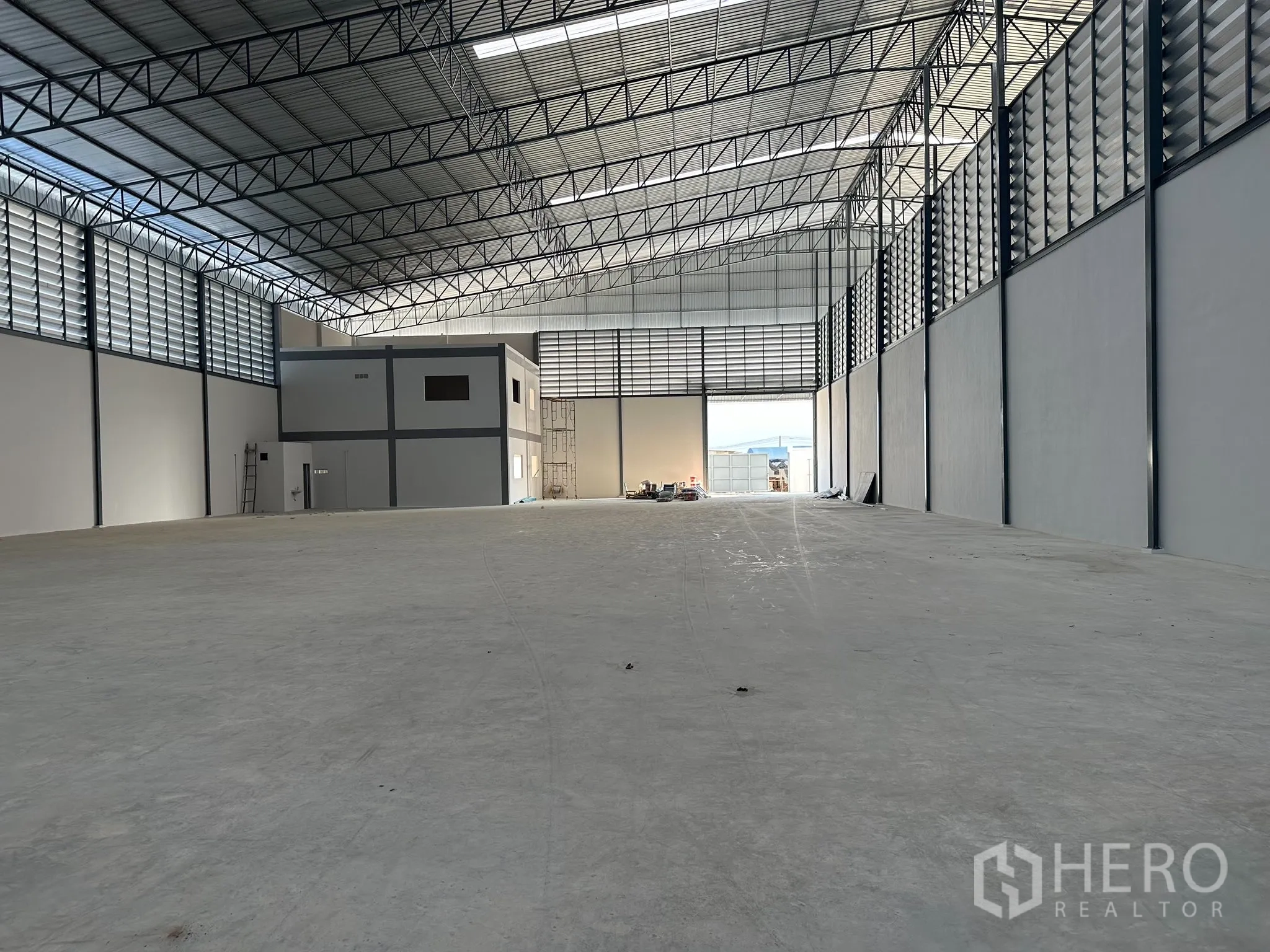 Factory for rent in Nong Khaem, Bangkok - Warehouse view toward large entry and two‑storey office block, bright natural light and clear span roof.