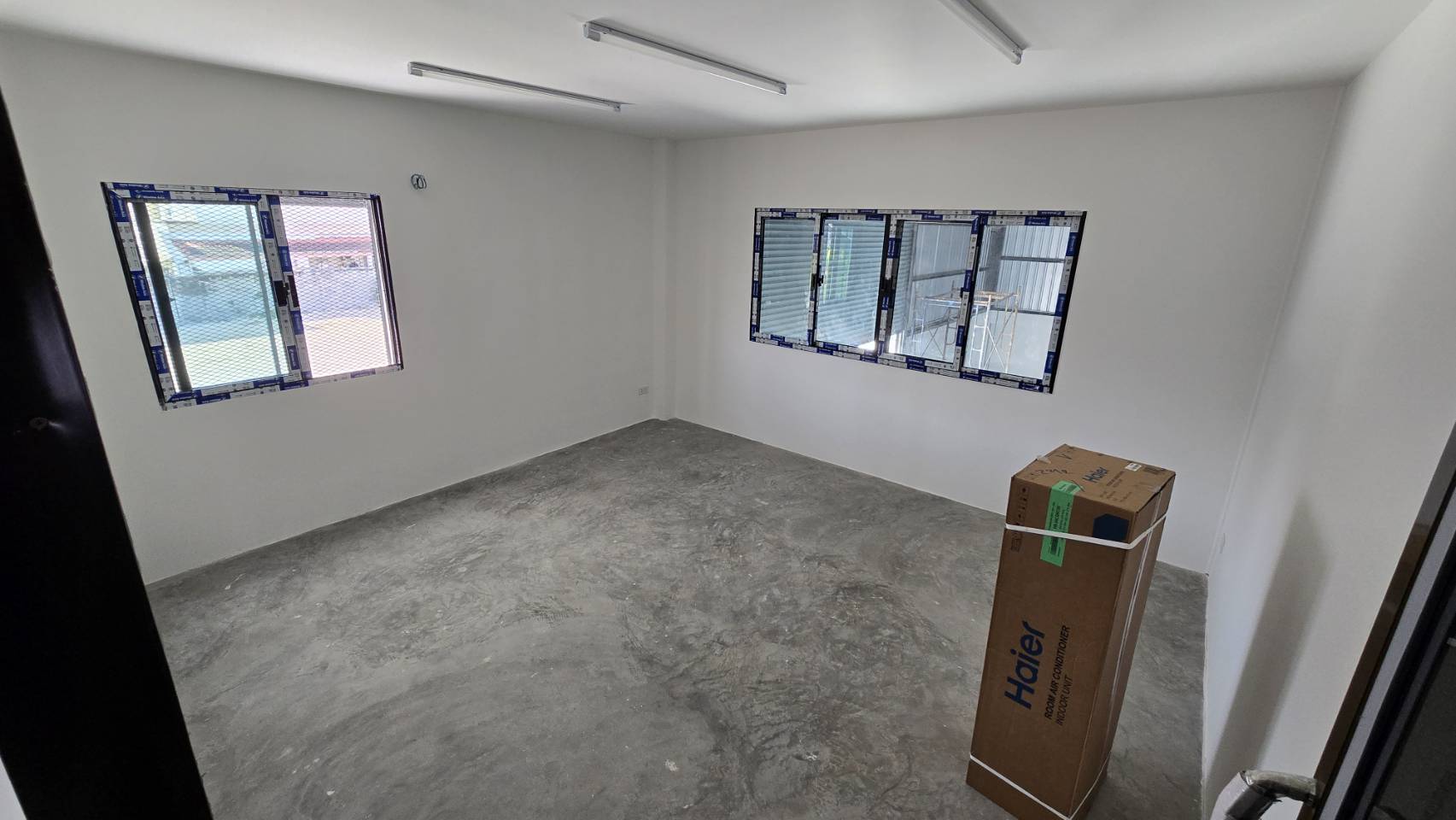 Warehouse for rent in Bang Phli, Samut Prakan - Bright office room inside the warehouse with white walls, multiple sliding windows, and unfinished concrete flooring.