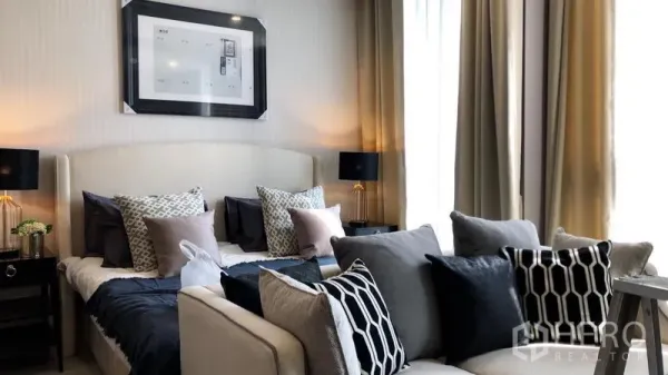 Condominium for rent in Pathum Wan, Bangkok - Studio sleeping area with upholstered bed, sofa and large curtained windows.