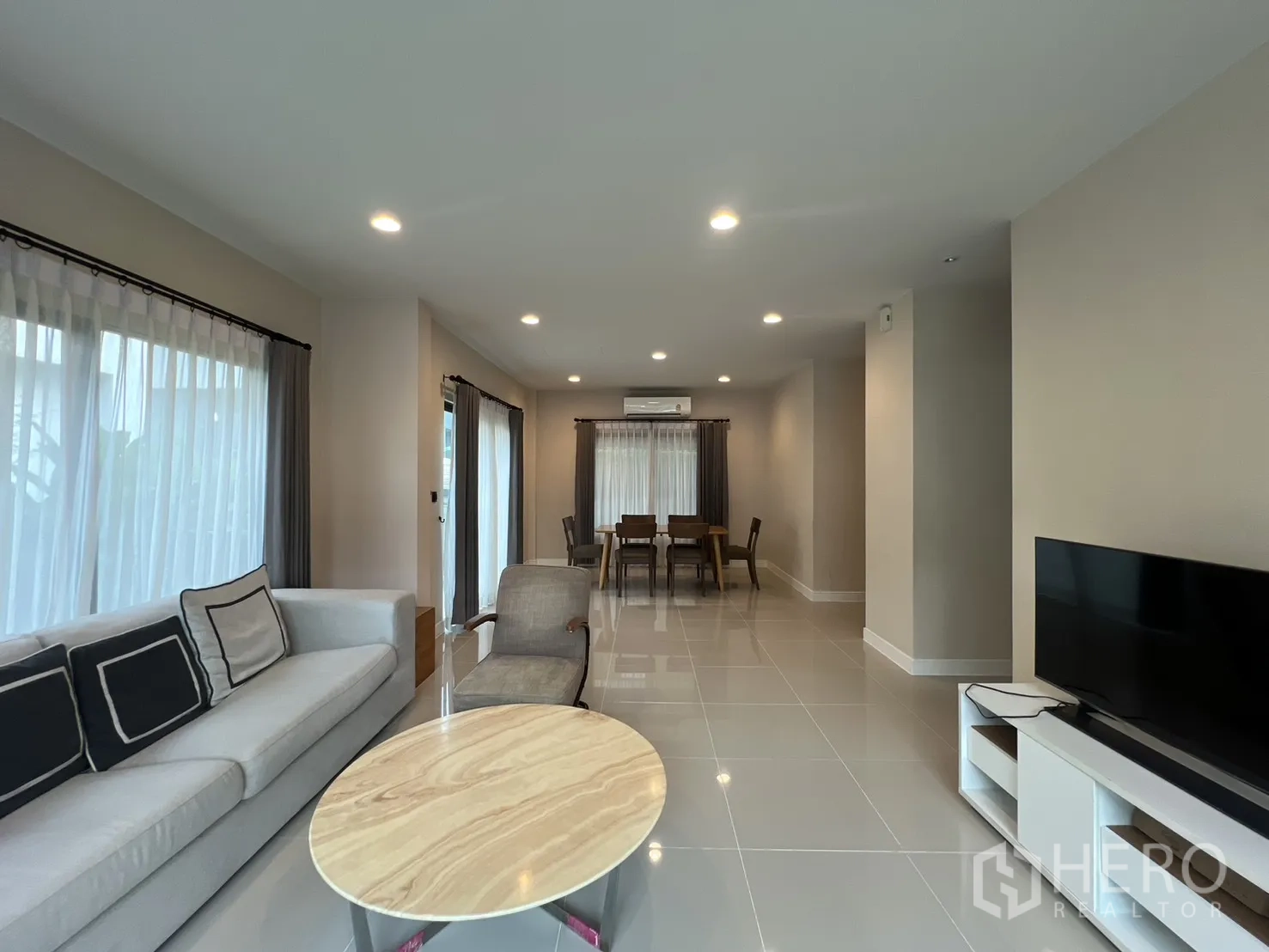 Detached House for rent in Bang Kapi, Bangkok - Open-plan living and dining room with sofa, TV unit and glossy tile floors.