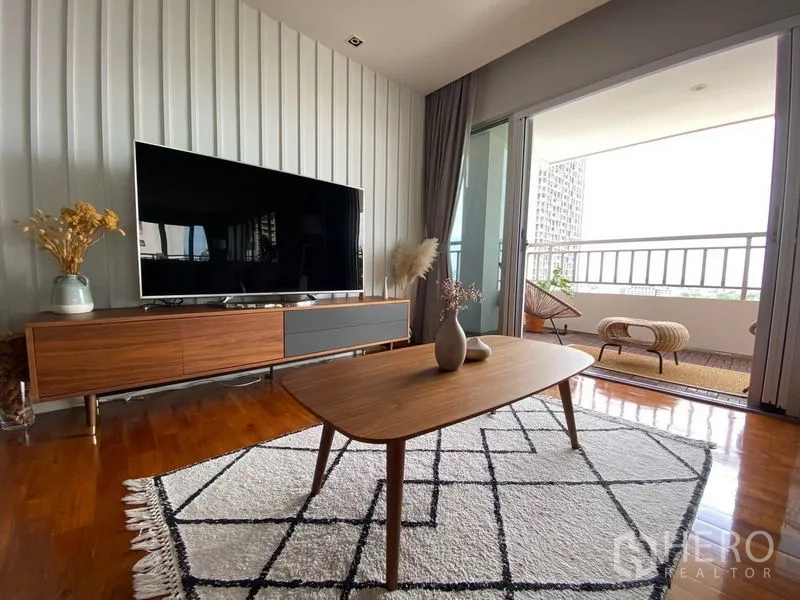 Condominium for rent in Sathon, Bangkok - TV lounge with mid-century console and coffee table opening onto the balcony.