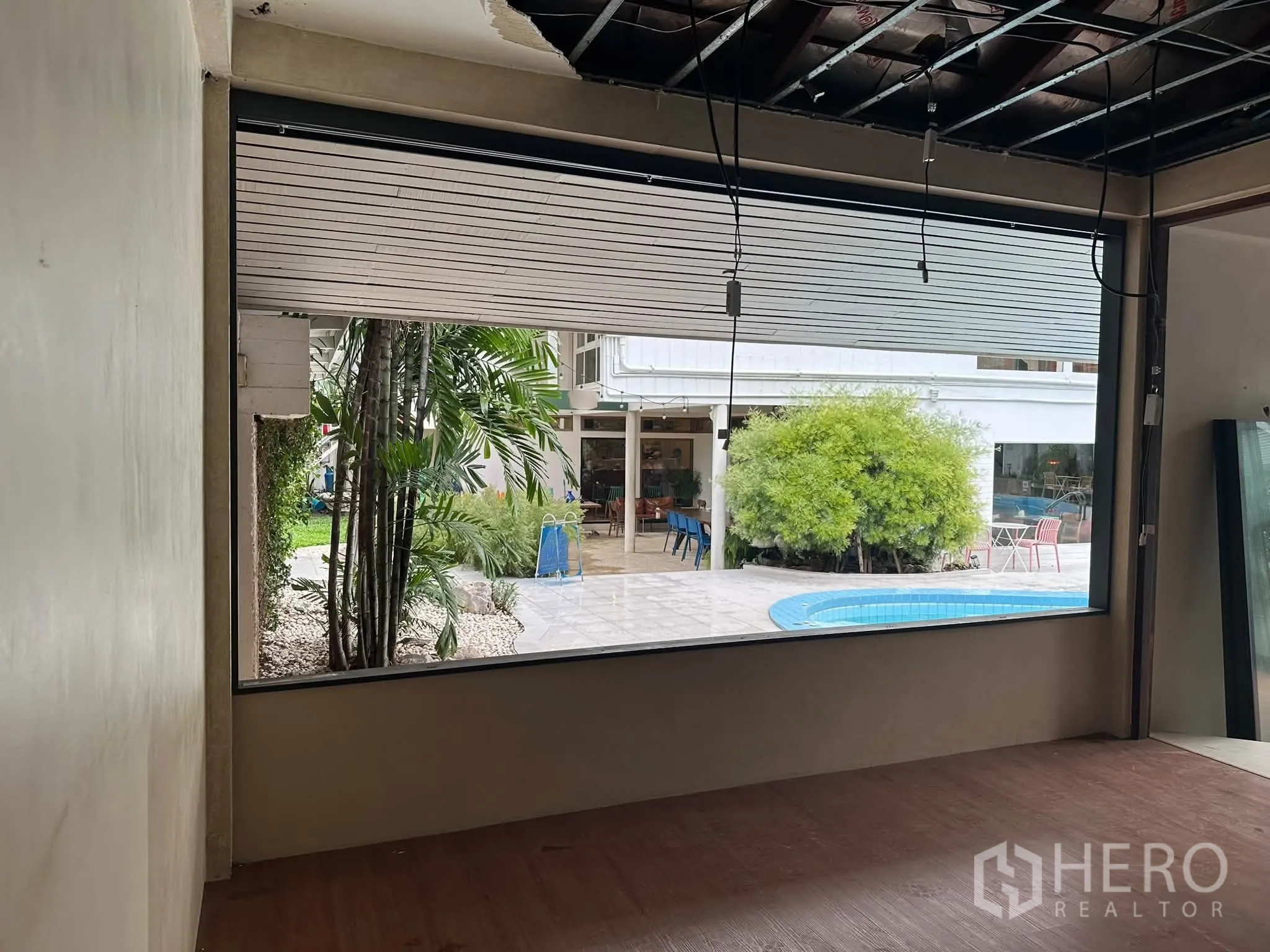 Retail Space for rent in Khlong Toei, Bangkok - Large window opening to a poolside courtyard with greenery and tiled terrace.