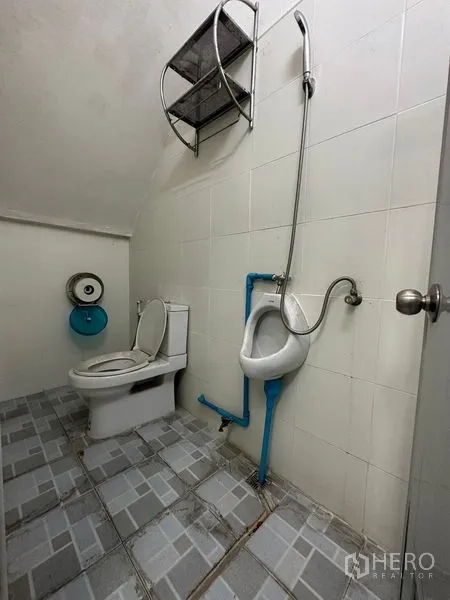 Shophouse for rent in Bang Na, Bangkok - Second bathroom with toilet, urinal and handheld shower on a tiled floor.