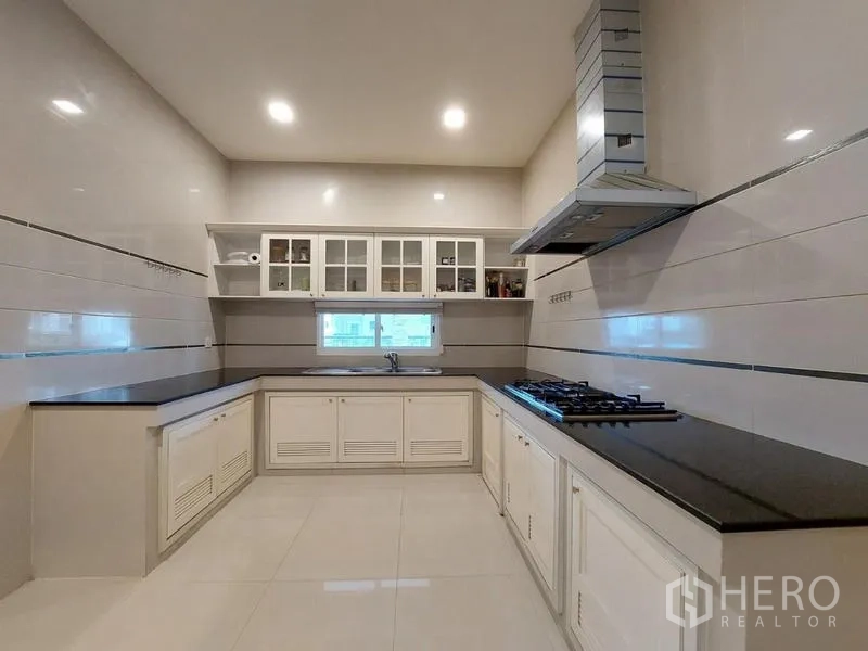 Detached House for rent in Bang Phli, Samut Prakan - Modern Thai kitchen with gas hob, range hood and black countertops