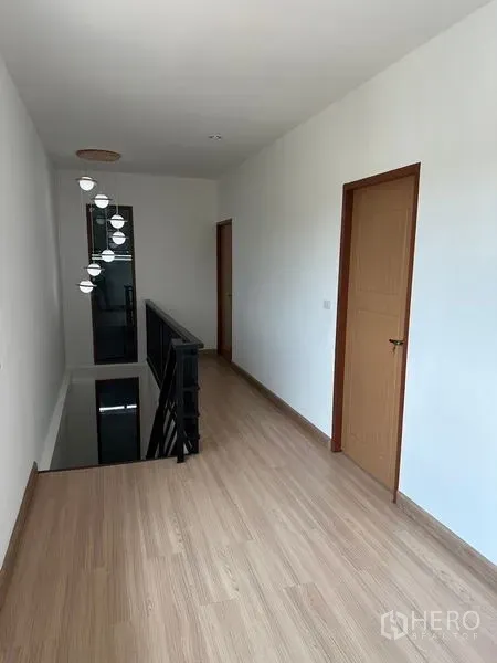 Warehouse for rent in Lam Luk Ka, Pathum Thani - Second-floor corridor with wood flooring, white walls and doors beside a stair railing.