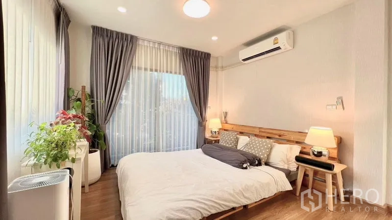 บ้าน ให้เช่าหรือขายในBang Khen, Bangkok - ห้องนอนสว่าง เตียงไม้ เครื่องปรับอากาศ หน้าต่างบานใหญ่ และต้นไม้ในบ้าน