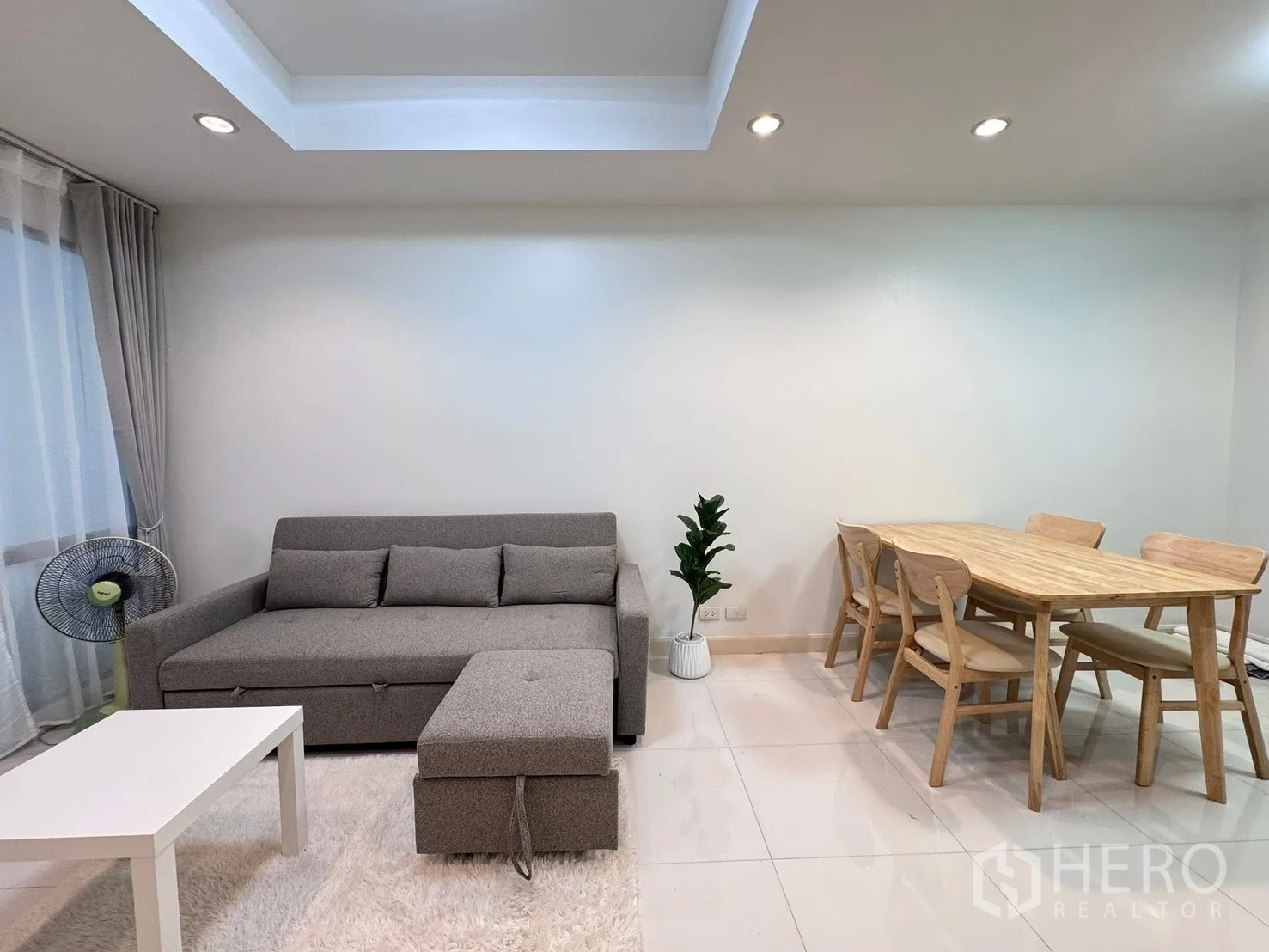 Townhouse for rent in Phra Khanong, Bangkok - Open-plan lounge and dining zone with sofa, fan, and natural light.