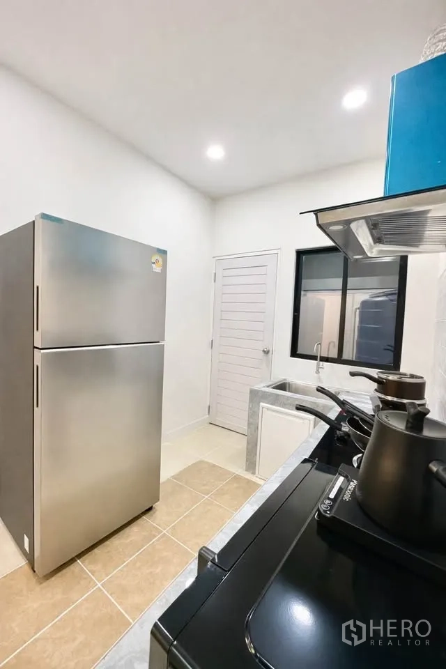 Detached House for rent in Huai Khwang, Bangkok - Kitchen angle showing refrigerator, windowed sink and stovetop.