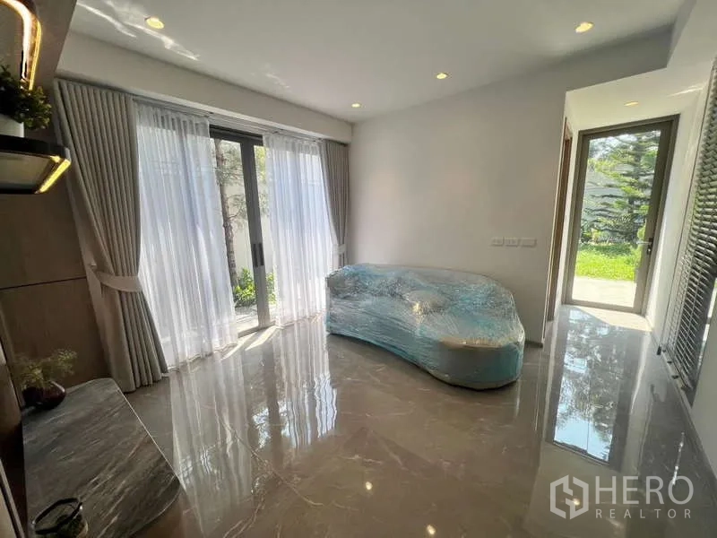 Townhouse for rent in Phra Khanong, Bangkok - Ground-floor multipurpose room with glossy tile flooring and sliding doors to the garden.