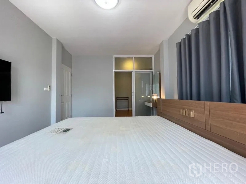 Detached House for sale in Lam Luk Ka, Pathum Thani - Sunlit bedroom with large bed, air conditioning and door to ensuite or closet.