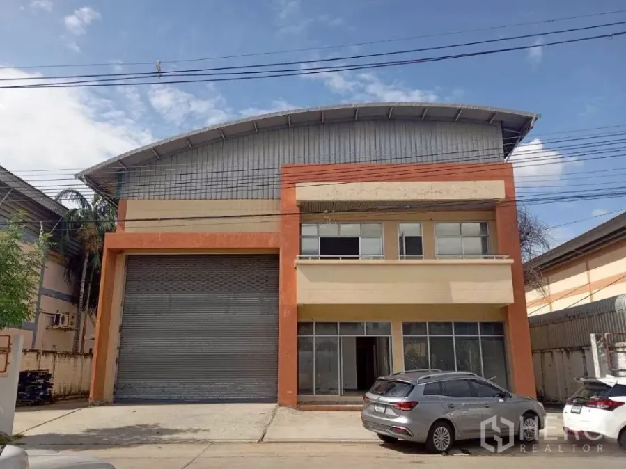 Factory for rent in Khlong Luang, Pathum Thani - Street-facing factory with large roller shutter, two-storey office front and parking area.